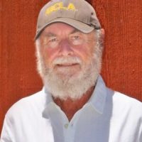 Professor Donald Shoup over a red background wearing a UCLA hat.